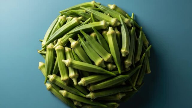 A top down view of fresh organic okra arranged in a circular pattern against a solid blue backdrop. This sequence of images shows the transition from bright to dramatic lighting