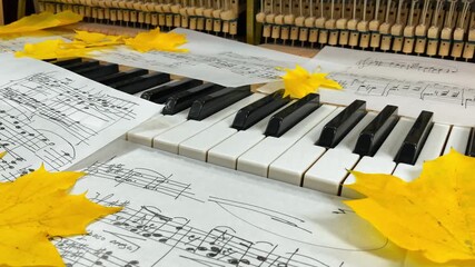 An Old Upright Piano in Autumn: Handwritten sheet music and vibrant maple leaves rest on the keys, with the inner hammer mechanism visible, creating a nostalgic scene of seasonal musical inspiration