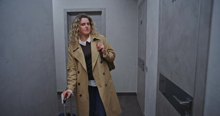 Guest With Curly Hair Carries Backpack And Pulls Trolley Bag While Navigating Hotel Corridor. After Checking Door Numbers, Unlocks and Enters Room. Concept Travel Comfort, Check In Routine. Handheld.