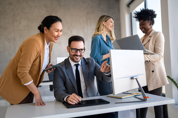 Happy multiethnic businesspeople laughing while collaborating on a new project in an office.