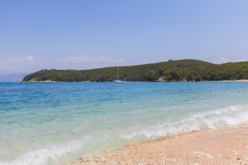 Crystal clear turquoise waters meet golden sandy beach with lush green hills .