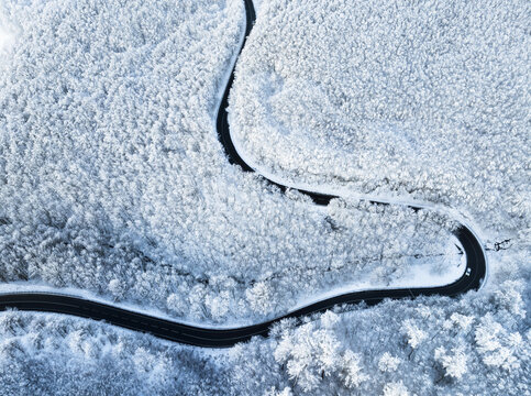 Aerial view of winter forest covered in snow at sunrise with road and ski slope - Powered by Adobe