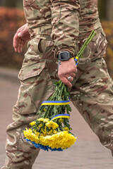 Ukrainian army. Memory of the dead. Russian-Ukrainian war. Ukrainian soldiers. Flowers in a man's hand. Honoring the memory. Posthumous ceremonies. Funeral bouquet. Military brotherhood.