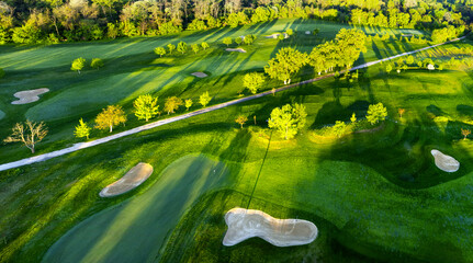 Aerial view of sunset over golf course with spring colored trees and lakes