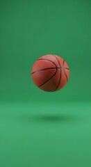 Fototapeta premium A basketball is suspended in mid-air against a solid green background, creating a dynamic and energetic visual suitable for sports or athletic themes