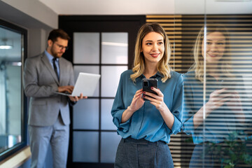 A confident businesswoman leads her busy office life, multitasking with smartphone communication
