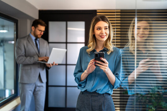 A confident businesswoman leads her busy office life, multitasking with smartphone communication