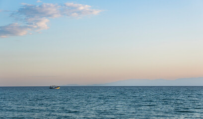 A boat is floating on the ocean in a calm, clear day