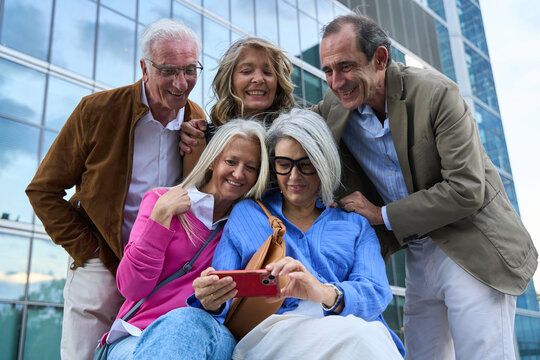 Senior friends together looking at smartphone outdoor