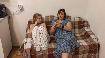 Woman and girl sitting on sofa and engaging in conversation indoors  