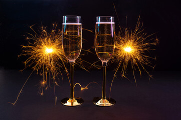 Happy New Year 2026, New Year's Eve holiday greeting card celebration. Sparklers firework, champagne glasses on black background