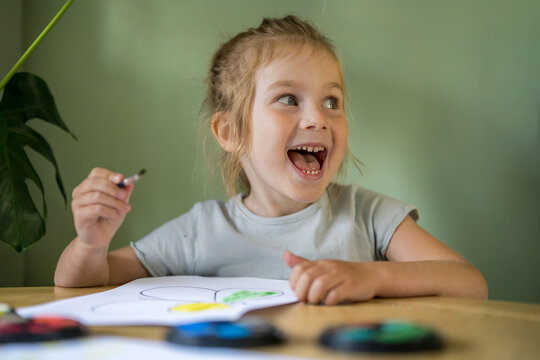Smiling child drawing and painting at home with creative expression