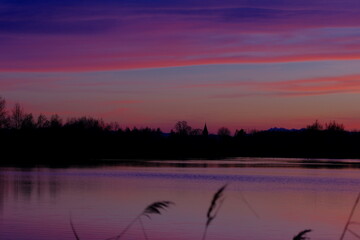 Pastelowy zachód słońca z konturami drzew, wieży kościelnej i Tatrami w tle