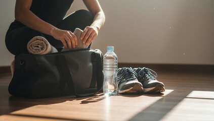 Woman packing a gym bag with fitness essentials for a workout. Active and healthy lifestyle concept with copy space