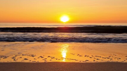 Golden sunset over calm ocean waves with warm glowing reflections on sandy beach creating peaceful coastal evening scenery - Powered by Adobe