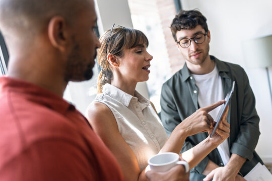 Team collaborating and brainstorming with tablet in startup office