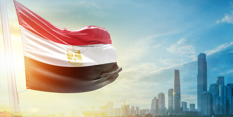 Egypt flag wavering in beautiful clouds with building skyline. The flag with drone shot in beautiful sky. Egypt national flag for independence day.