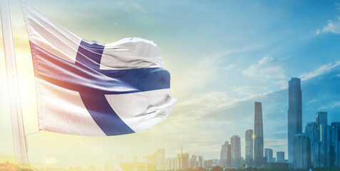 Finland flag wavering in beautiful clouds with building skyline. The flag with drone shot in beautiful sky. Finland national flag for independence day.