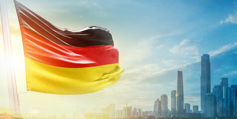 Germany flag wavering in beautiful clouds with building skyline. The flag with drone shot in...