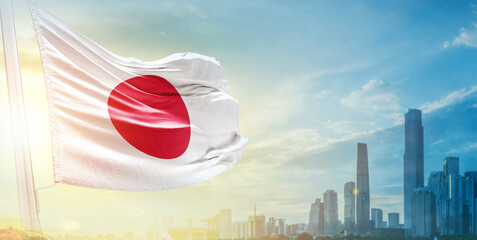 Japan flag wavering in beautiful clouds with building skyline. The flag with drone shot in beautiful sky. Japan national flag for independence day.