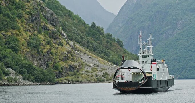 Aurlandsfjord car ferry approaching in a narrow Norwegian fjord on an overcast day