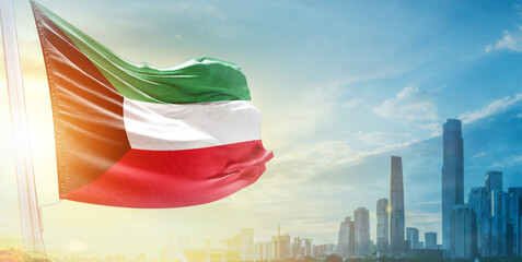 Kuwait flag wavering in beautiful clouds with building skyline. The flag with drone shot in beautiful sky. Kuwait national flag for independence day.