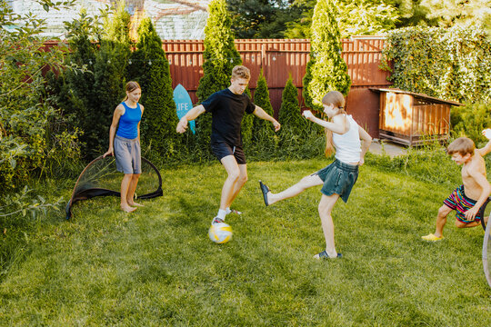 Teens and friends playing football together in backyard in summer