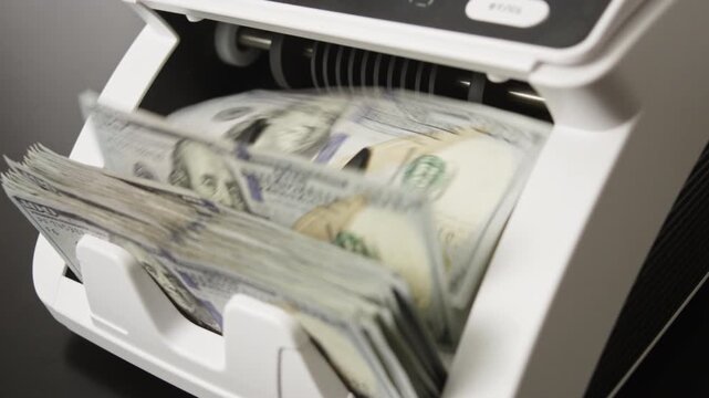 Hundred dollar bills moving through counting machine. Money counting processing. Hundred dollar banknotes motion in counting machine. American dollars in cash counter. USD bills. American currency.