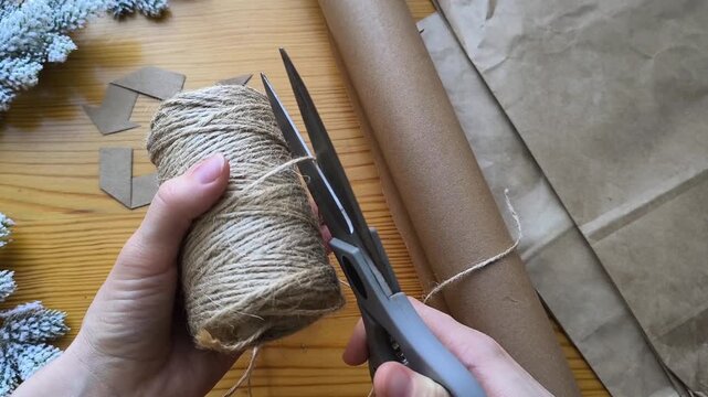 Scissors cut a piece of twine from a skein. Eco-friendly gift wrapping materials. Recycling.