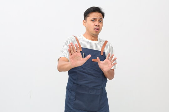 Asian man wearing apron, raising hands, dismissive gesture, disgusted expression, isolated white background. - Powered by Adobe
