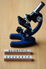 scientific research. words written on wooden blocks next to a microscope