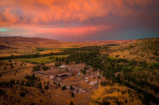 Aerial view of a tranquil valley bathed in the warm glow of sunset, with rolling hills and a small community nestled below, Tygh Valley, Oregon, United States.