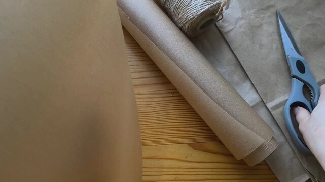 Gift wrapping in eco-friendly materials against the background of a recycling symbol and Christmas tree branches