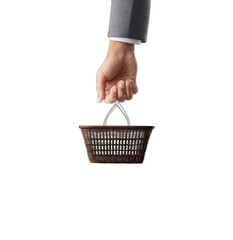 Fototapeta premium Close-up of a hand in a suit sleeve holding a small brown empty basket on black