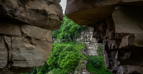 a natural rock shelter framing a lush green landscape of natural landmark.