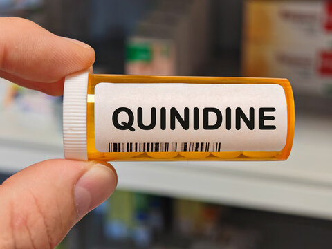 orange plastic Box of QUINIDINE tablets on a hospital pharmacy table used to treat irregular heart rhythms an antiarrhythmic. PHARMACY warehouse