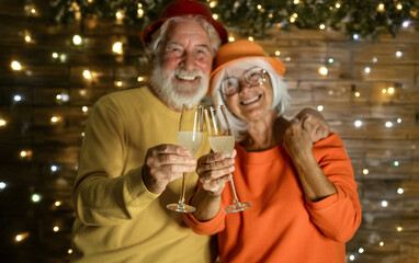 Happy defocused senior couple celebrating together with sparklers wine, smiling and enjoying a festive night against a backdrop of warm decorative lights