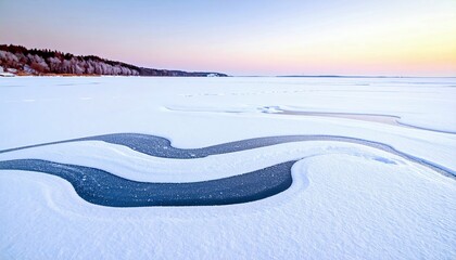 Abstract patterns of snow and ice on a frozen lake at sunrise with a distant treeline