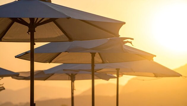 Beach umbrellas glow in the warm, golden light of sunset, creating a serene vacation vibe