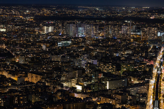 Aerial view of buildings illuminated with a golden glow cast by streetlights, stretching across the cityscape like rivers of light, Paris, Ile-de-France, France.