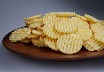 A pile of corn chips on a clay plate. Round corn chips.