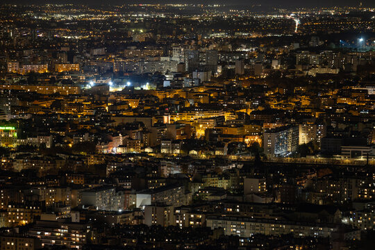 Aerial view of a captivating urban tapestry woven with glittering lights across the cityscape, illuminating the night sky over the magnificent metropolis, Paris, Ile-de-France, France.