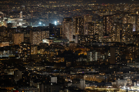 Aerial view of luminous windows puncturing the night across the city, a tapestry of urban life under a starlit sky, Paris, Ile-de-France, France.