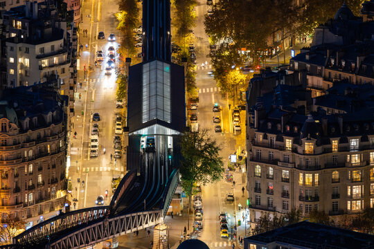 Aerial view of a vibrant city street illuminated with golden lights and bustling with cars and buildings, Paris, Ile-de-France, France.