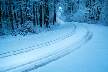 Tire tracks on the road covered with snow in the forest, Nowiny, Poland