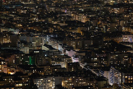 Aerial view of a densely packed urban landscape with illuminated buildings creating a tapestry of light and shadow, Paris, Ile-de-France, France.
