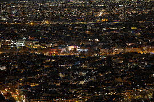 Aerial view of a tapestry of twinkling city lights, illuminating the urban expanse beneath the silhouette of the Eiffel Tower, a beacon in the velvet night, Paris, Ile-de-France, France.
