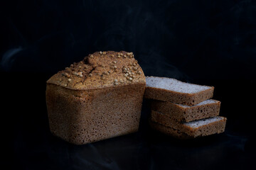 Half a loaf and pieces of sliced buckwheat bread on a black background.