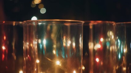 Close-up of glass candle holders with colorful bokeh lights in the background, creating a warm, inviting atmosphere for any occasion.
