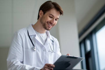 Male doctor smiling while holding tablet in clinic